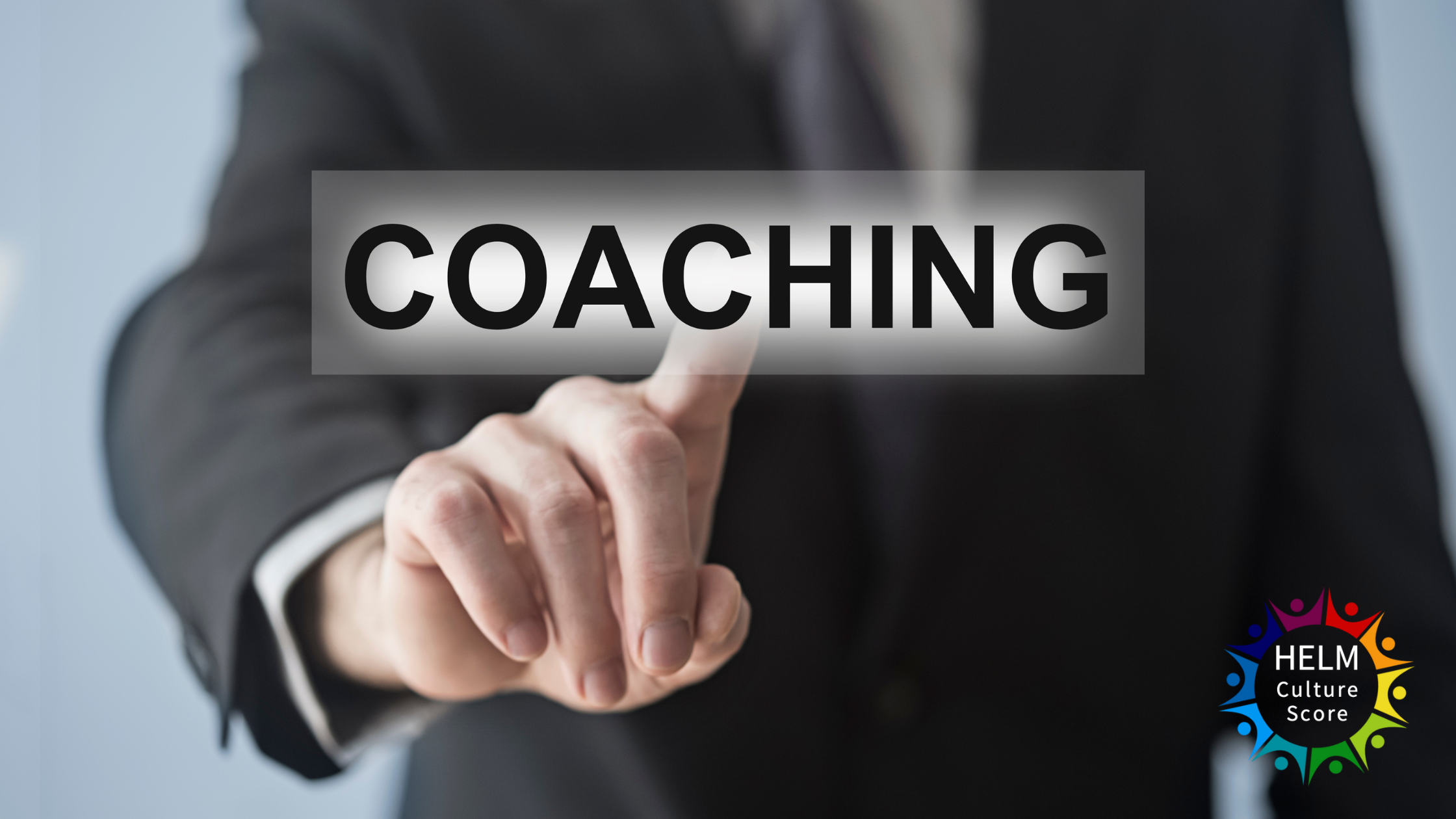 Business professional pointing to the word coaching, symbolising coaching success, with HELM Culture Score logo.